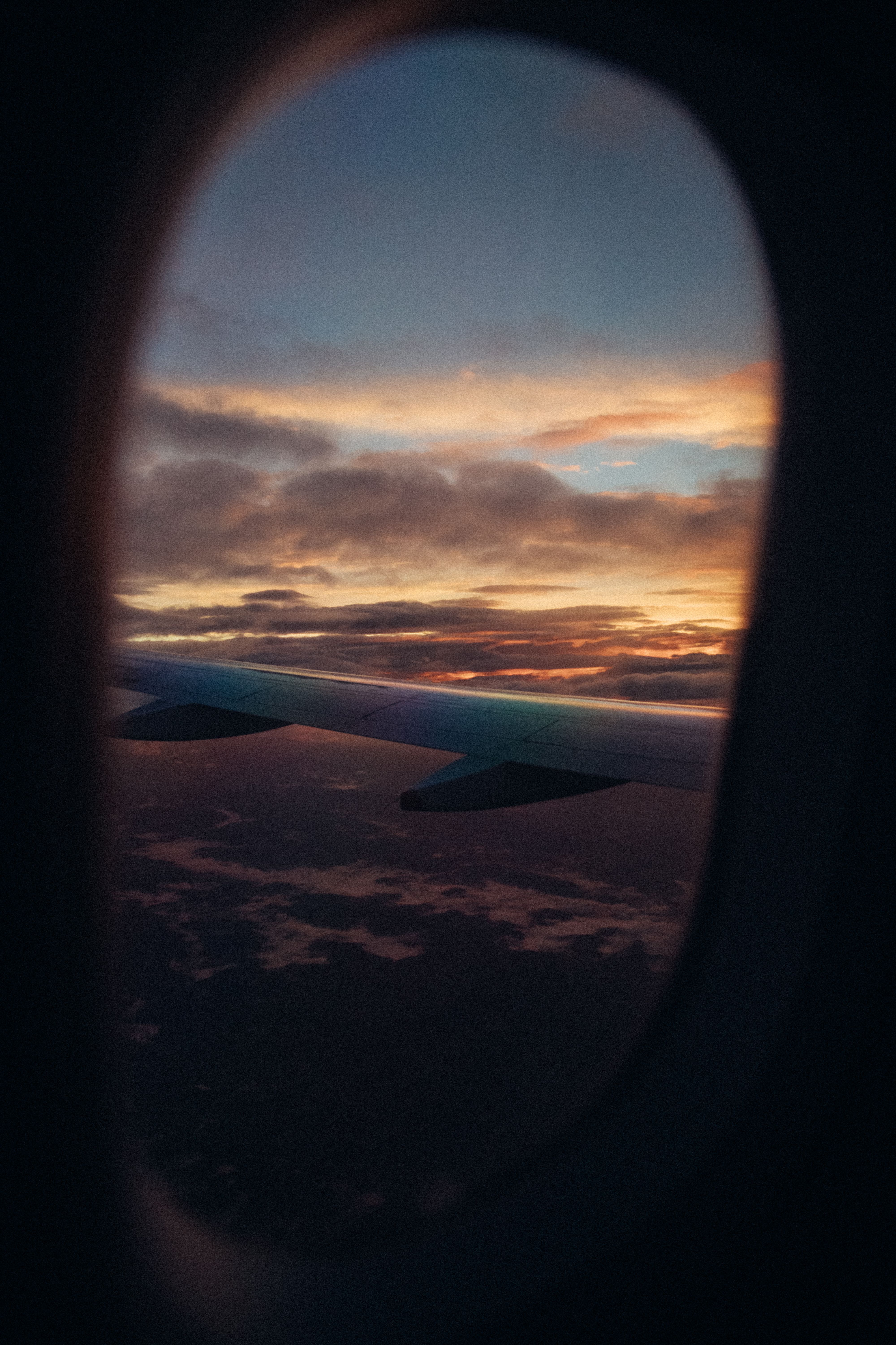 Sunset sky and the aircraft wing seen through an airplane window